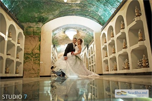 Жених обнимает невесту под аркой винного подвала