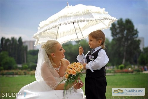 Невеста рядом с мальчиком,  держащим зонтик