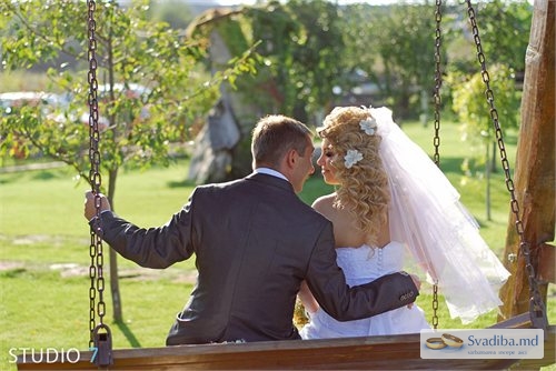 Жених обнимает невесту на качелях
